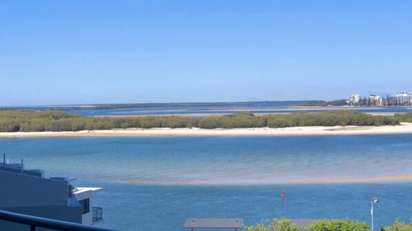 A coastal view with a clear sky, a sandy beach, and a body of water.