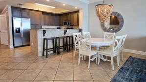 Una cocina moderna con una isla central, taburetes de bar y una mesa de comedor con sillas.