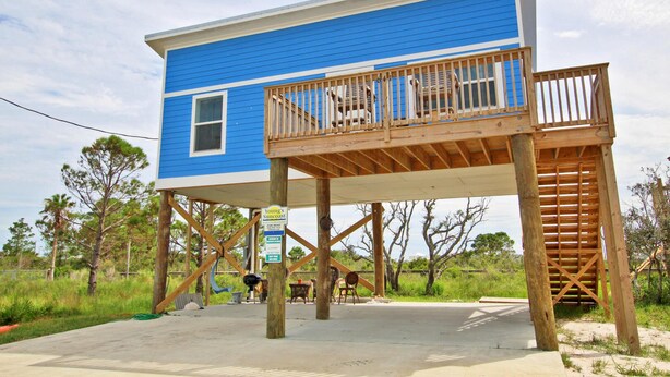 A two-story blue building with a wooden deck and a staircase.