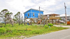 A two-story house with a blue exterior and a wooden deck.