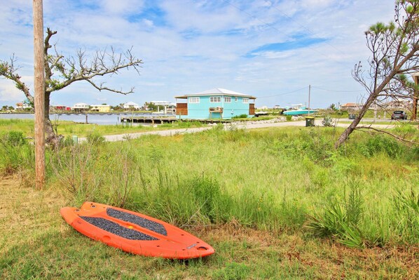 A coastal house with a grassy area in front, a red kayak, and a clear sky. - La Casita Azul by Youngs Suncoast (Gulf Shores)