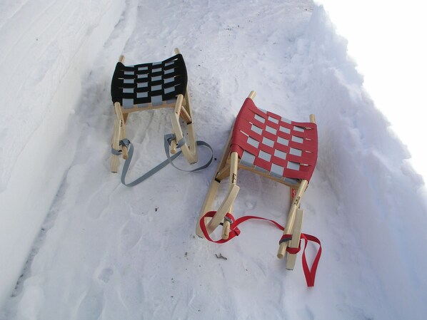 Zwei Holzschleuder mit gewobenen Sitzen und Bindungen liegen im Schnee.