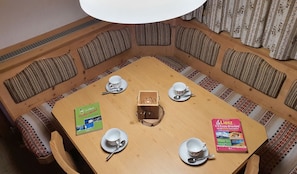 Ein runder Holztisch mit vier weißen Tassen und Untertellern, zwei Büchern und einer hölzernen Schatulle in der Mitte.
