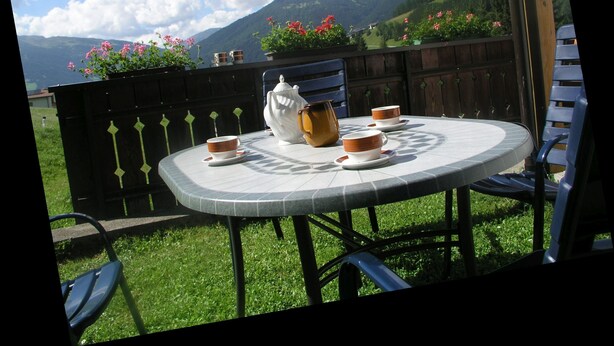 A round outdoor table with a view of mountains and flowers. - Cozy Angererhof: Near Drei Zinnen - Dolomites Apartment (4P) - ALPINE (Kartitsch)