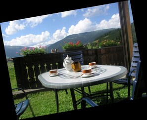 A round outdoor table with a view of mountains and flowers. - Cozy Angererhof: Near Drei Zinnen - Dolomites Apartment (4P) - ALPINE (Kartitsch)