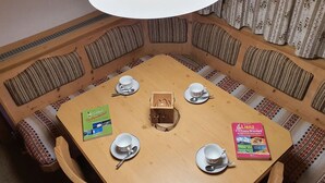 A round wooden table with four white cups and saucers, two books, and a central wooden box. - Cozy Angererhof: Near Drei Zinnen - Dolomites Apartment (4P) - ALPINE (Kartitsch)