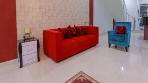 A modern living room with a red sofa, a blue armchair, and a patterned rug.