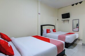 Habitació d'hotel amb dos llits, cada un amb roba de llit vermella i blanca, un televisor de pantalla plana penjat a la paret i un mirall sobre els llits.