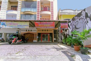 Hotel amb una placa publicitària que anuncia tarifes d'habitació, servei de bugaderia i tintoreria, i una zona d'aparcament amb motos.