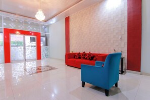 A modern lobby with a red and white color scheme, a blue armchair, and a patterned wall.