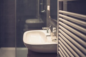 Ein Badezimmer mit einem weißen Waschbecken, einem Spiegel und einem Handtuchhalter.