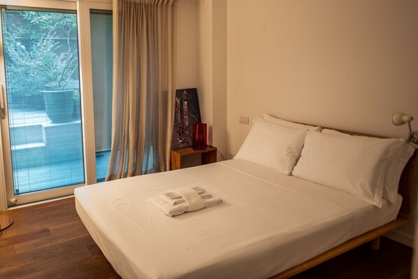 A hotel room with a bed, a nightstand, a lamp, and a window with curtains. - L'Archè Comfort&Relax, Luxury loft Porta Venezia (Milano)