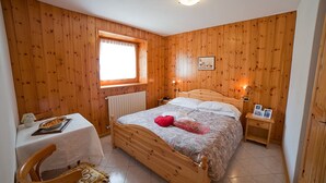 A wooden-paneled bedroom with a bed, bedside table, and a window.