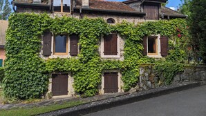 Ein zweistöckiges Gebäude mit einer Stein-Fassade, die teilweise von Efeu bewachsen ist.