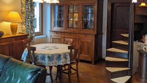 Eine traditionelle Küche mit Holzschränken, einem Esstisch mit Stühlen, einer Treppe und einer Lampe.