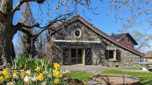 Ein Steinhaus mit rundem Fenster und einer Tür, umgeben von einem Garten mit Narzissen.