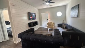 A living room with a flat-screen TV, a ceiling fan, and a sofa.
