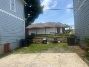 A backyard with a barbecue grill, a stone wall, and a fenced area. - Basic 4BR Home 15 Min Downtown ATL Sleeps 8+ (Atlanta)