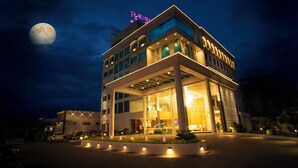 A modern hotel with a prominent sign, large windows, and a well-lit entrance. - Regenta Central Somnath (Veraval)