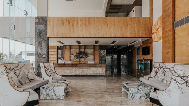 A modern lobby with marble flooring, wooden reception desk, and seating area with marble coffee tables. - Regenta Central Somnath (Veraval)