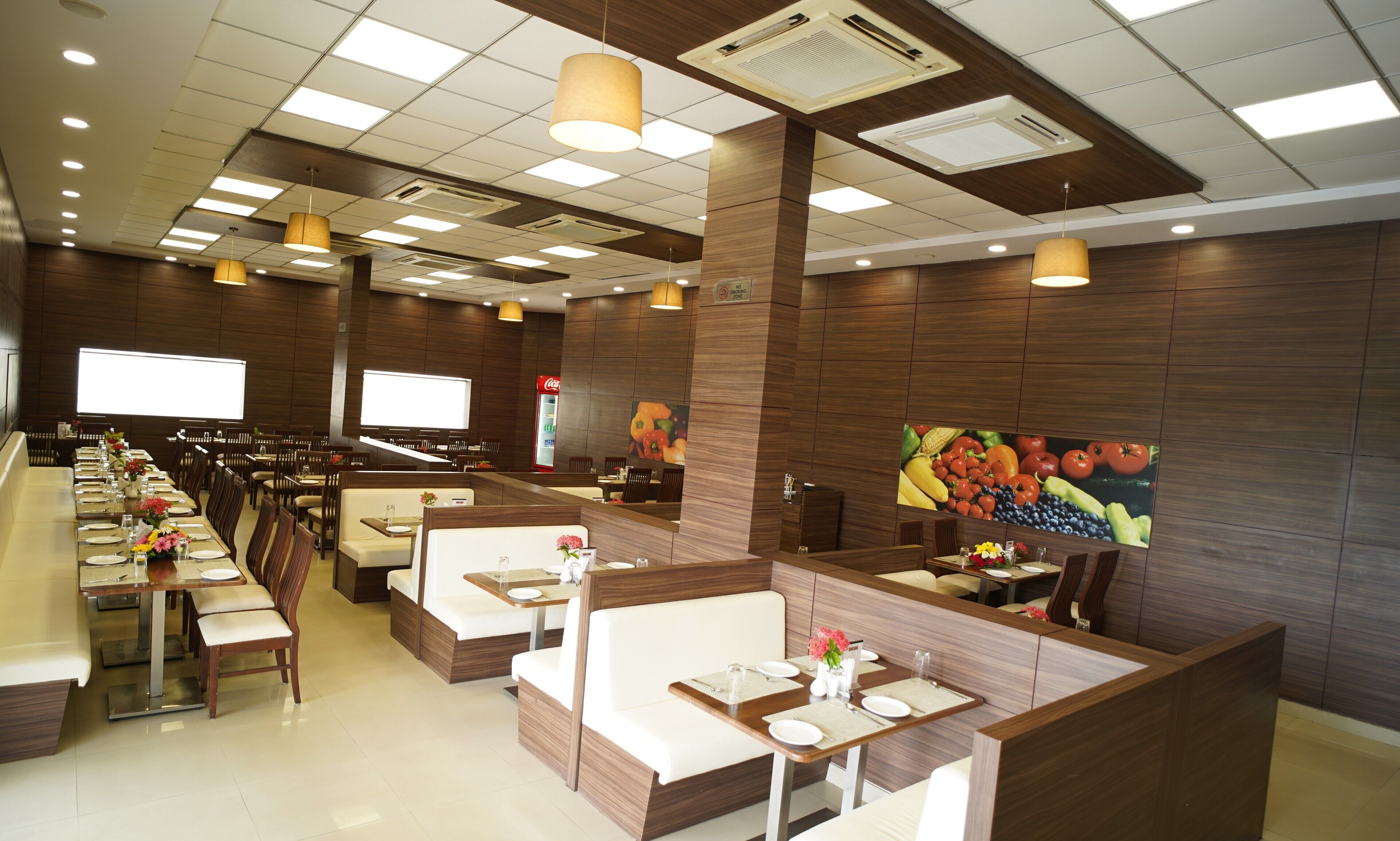 A restaurant with multiple dining booths and tables, wooden paneling, and a large fruit mural on the wall.