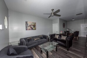 A modern living room with a sofa, a coffee table, and a ceiling fan.