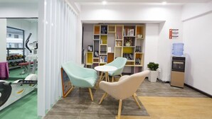 A room with two chairs, a small table, a bookshelf, and a water dispenser.