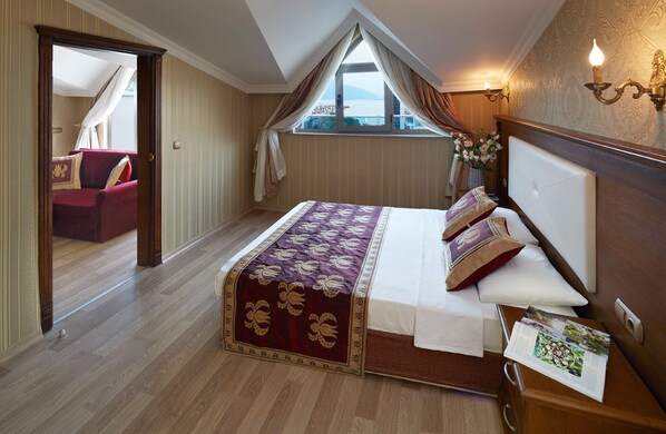 Un dormitorio con una cama grande, cabecera de madera, ventana con cortinas, mesita de noche y vistas al exterior.