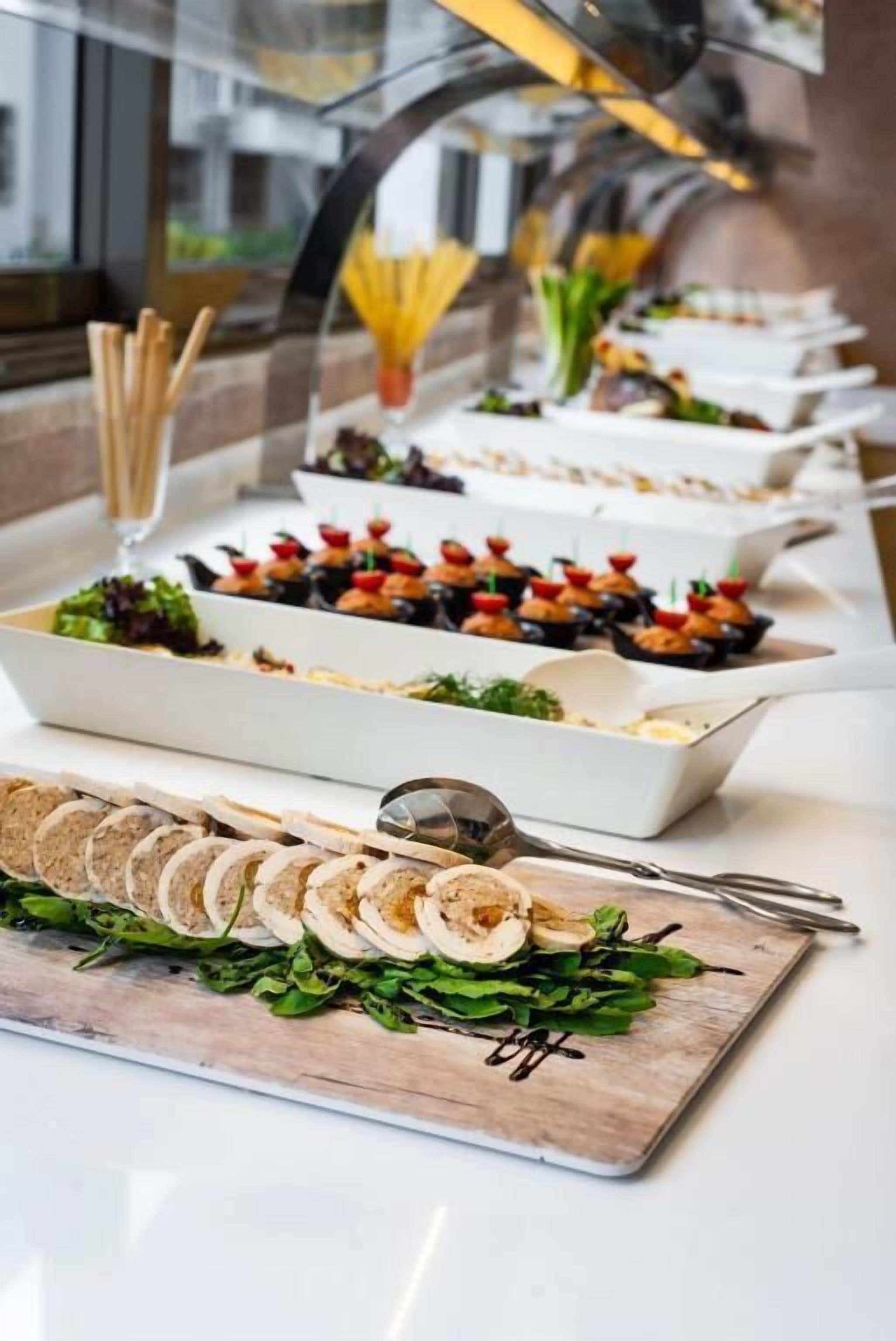 A buffet with various food options including salads, appetizers, and sliced meats.