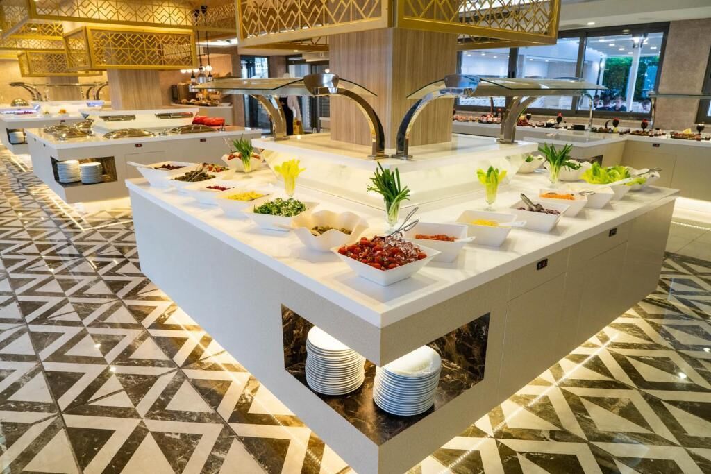 A buffet area with multiple serving stations, each with a variety of food items and fresh vegetables.