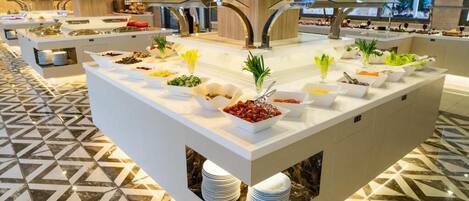 A buffet area with multiple serving stations, each with a variety of food items and fresh vegetables.