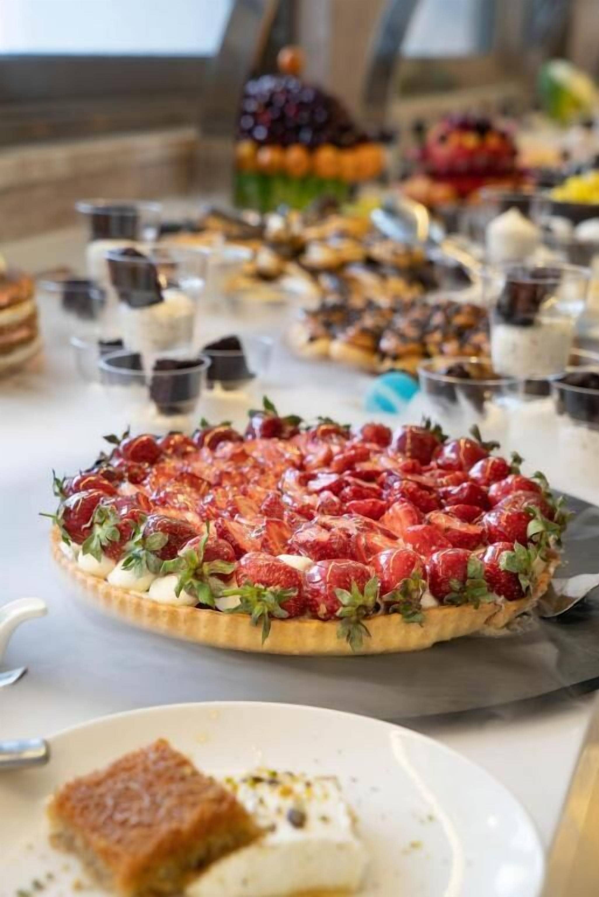 A buffet with various desserts, including a strawberry tart and other pastries.