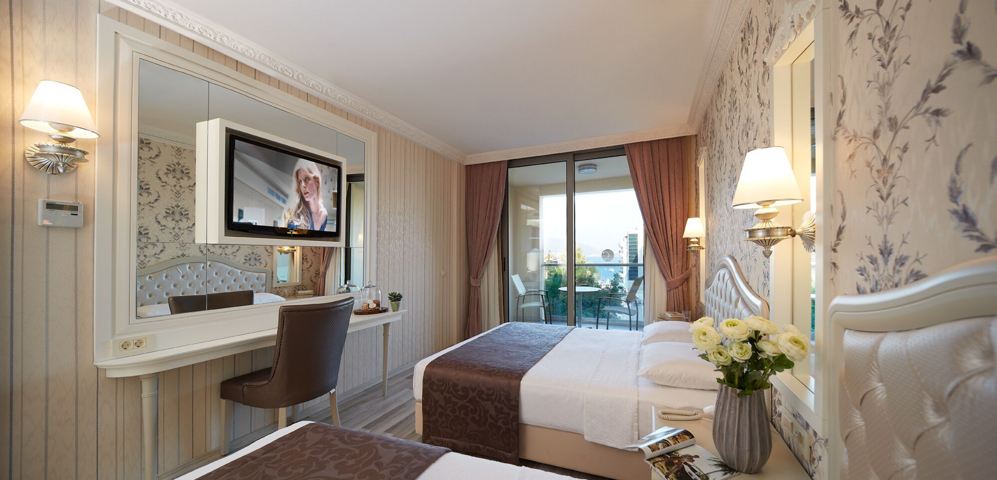 Ein Hotelzimmer mit Bett, Schreibtisch, Fernseher und Blick ins Freie.