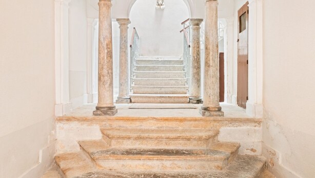 Eine prächtige Treppe mit Marmorsäulen, die zu einer höheren Etage führt.