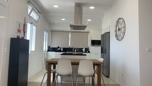 A modern kitchen with a dining table, two chairs, a black refrigerator, and a clock on the wall. - Casa da Paz - Fantastic view of Funchal Bay (São Gonçalo)