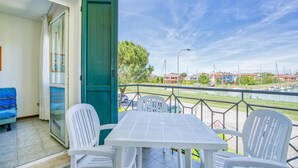A balcony with a table and chairs, a green door, and a view of a marina with boats. - 1 bedroom stunning apartment in Caorle (Caorle)