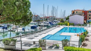 A marina with boats docked, a swimming pool, and surrounding buildings. - 1 bedroom stunning apartment in Caorle (Caorle)