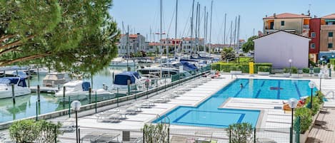 A marina with boats docked, a swimming pool, and surrounding buildings.