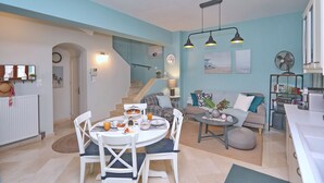 A modern living space with a dining area, kitchen, and staircase.