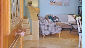 A modern living room with a staircase, a clock, and a view of the beach.