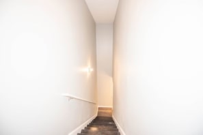 Eine enge Treppe mit weißen Wänden und einer Handläufe, die zu einer Empore führt.
