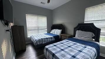 Une chambre avec deux lits, un ventilateur de plafond et un téléviseur fixé au mur.
