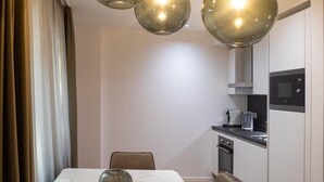 Een moderne eetruimte met een marmeren tafel, drie bolvormige hanglampen en een keuken op de achtergrond.