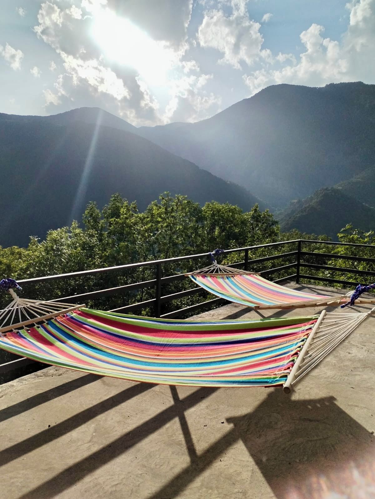 Una hamaca instalada en una plataforma de concreto con vista a la montaña.
