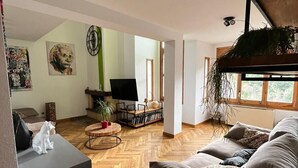 A spacious living room with a grey sofa, a black TV stand, and a wooden herringbone floor. - Spacious house (sleeps 7) with incredible view HUT6007971 (Aubinyà)