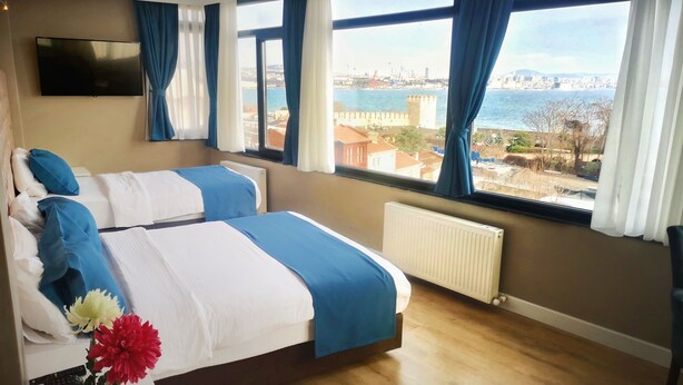 A hotel room with two beds, a TV, and large windows with a city and sea view. - Cape Palace Hotel (Istanbul)