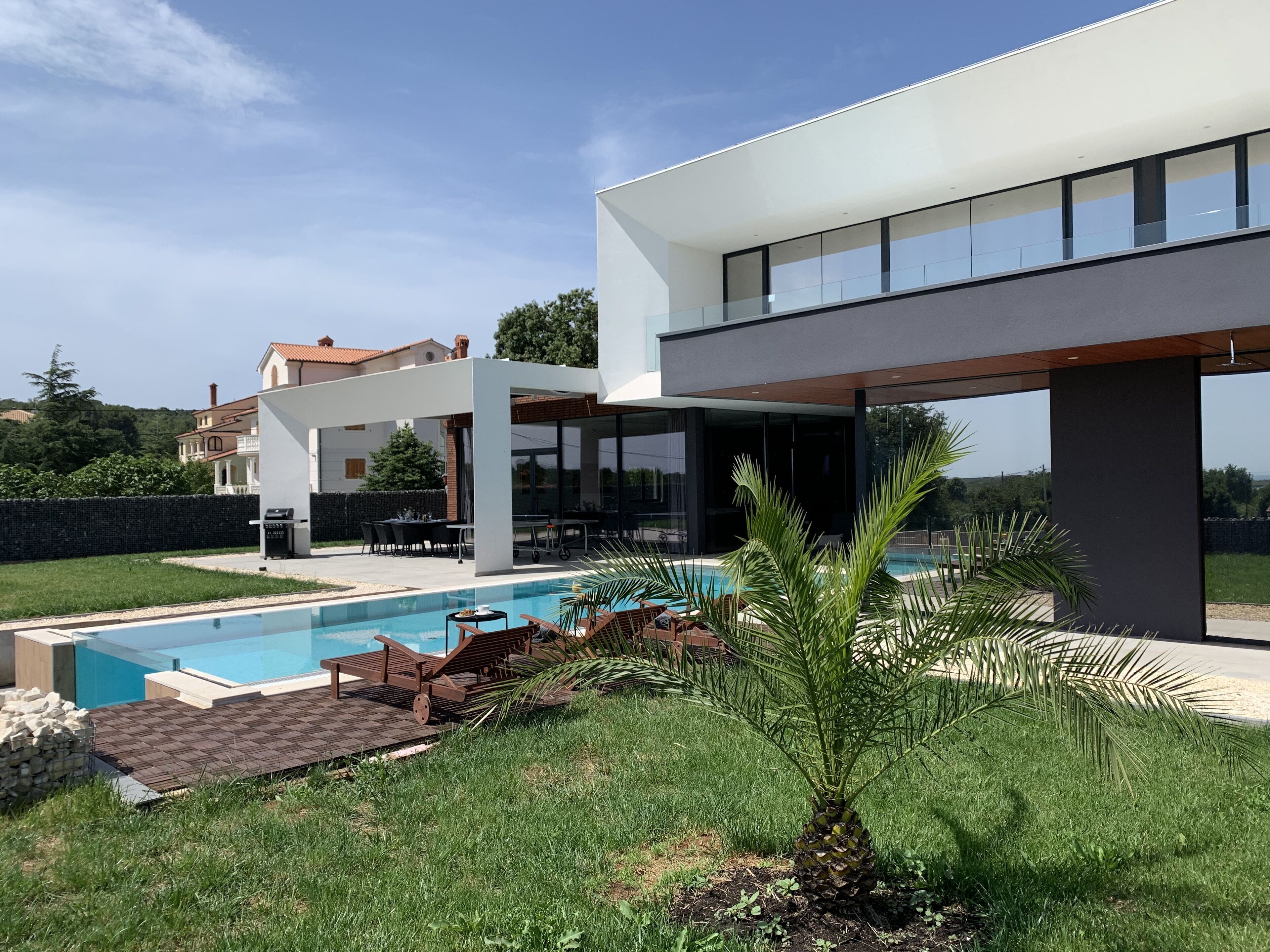 A modern house with a swimming pool, outdoor furniture, and a well-maintained garden.