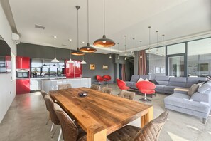 Una cocina moderna con armarios rojos, una mesa de comedor de madera e iluminación colgante.