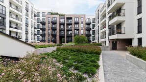 A modern apartment complex with multiple balconies, a landscaped garden area, and a paved walkway. - Stylish Studio for Two with a Balcony | Close to the Old Town (Kraków)