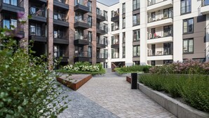 A modern apartment building with multiple balconies, a central courtyard with planters, and a brick facade. - Stylish Studio for Two with a Balcony | Close to the Old Town (Kraków)